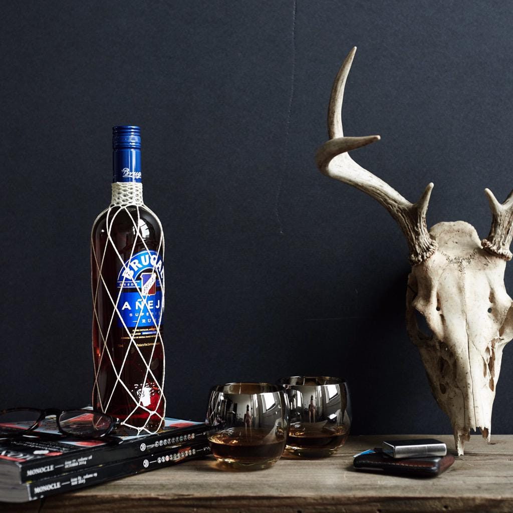 Brugal Anejo trong không gian thưởng thức Chai Brugal Anejo 700ml bày cùng ly rum trong không gian quầy bar tại nhà