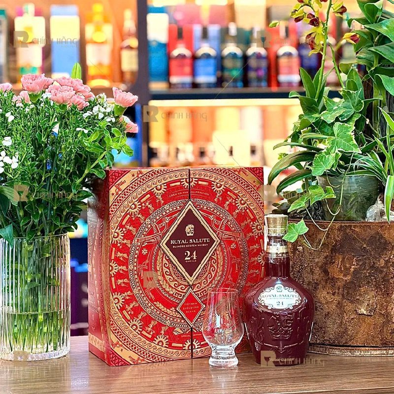 Hộp quà Chivas 24 Tết 2027 đặt cạnh chai sứ đỏ và ly tulip