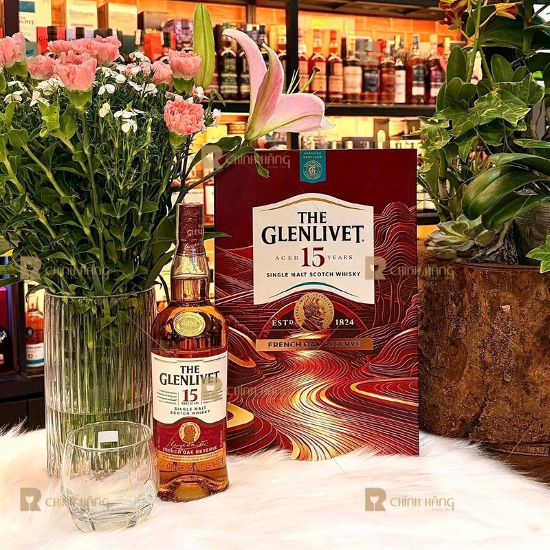 Hộp quà Glenlivet 15 Tết 2027 đặt cạnh chai rượu và hoa trang trí